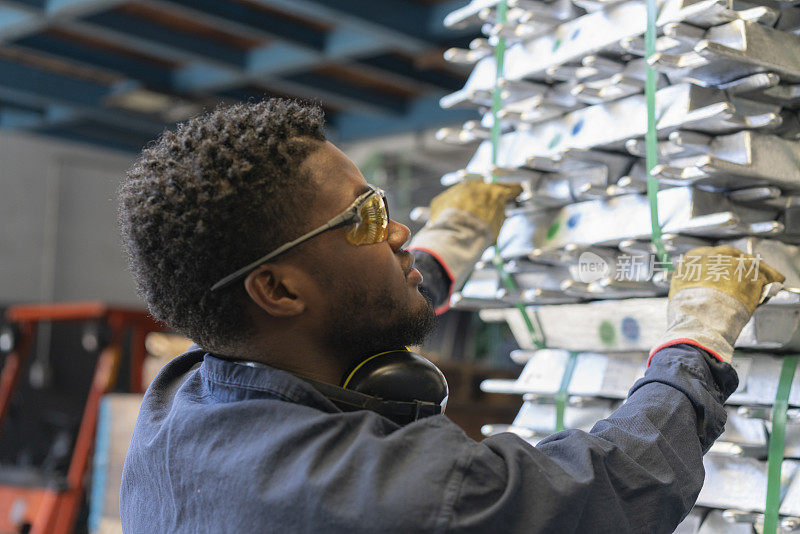 特写的非洲裔美国工人处理堆垛的金属注射零件在冶金厂