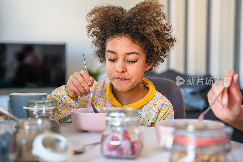 可爱的青少年混血女孩在家吃冰沙碗