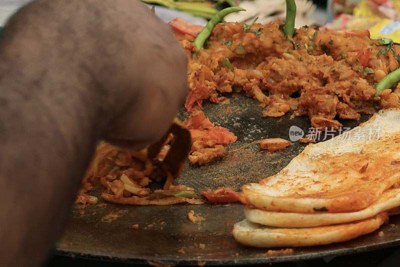 在户外用餐时，用金属锅铲加热着绿辣椒咖喱和印度烤饼面包