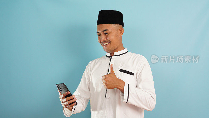 一个穆斯林男子对着手机竖起大拇指