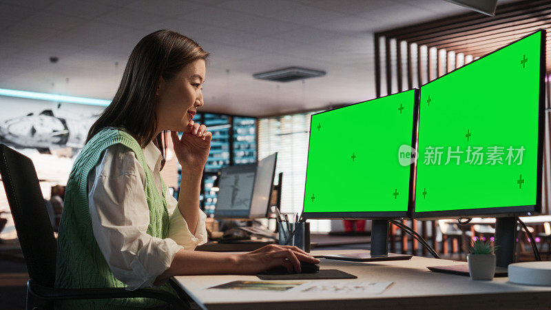 亚洲女游戏设计师使用桌面电脑绿屏Chromakey显示，设计角色在3D建模软件的生存视频游戏。在游戏开发办公室工作的女性
