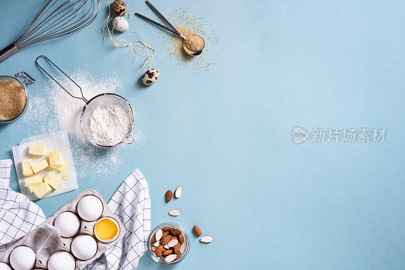 健康的烘焙材料-面粉，杏仁，黄油，鸡蛋，饼干放在蓝色的桌子上。