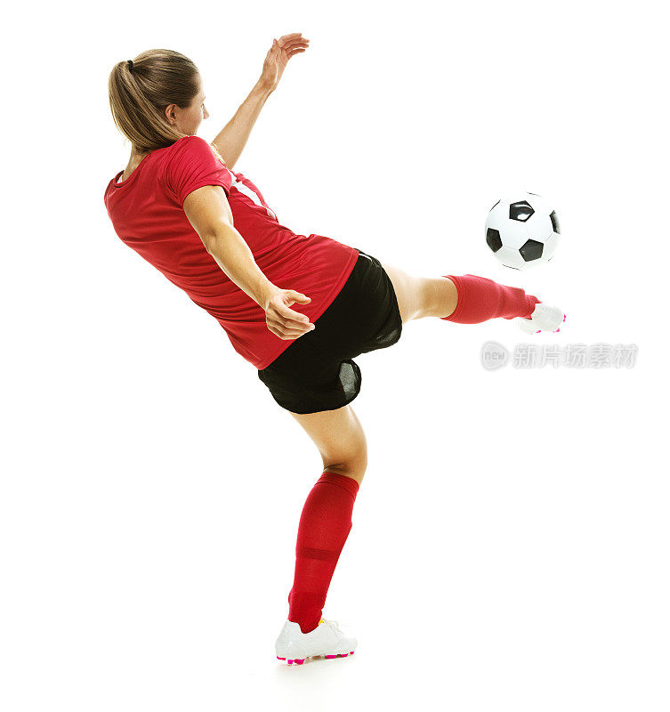 女足球运动员踢足球的后视图