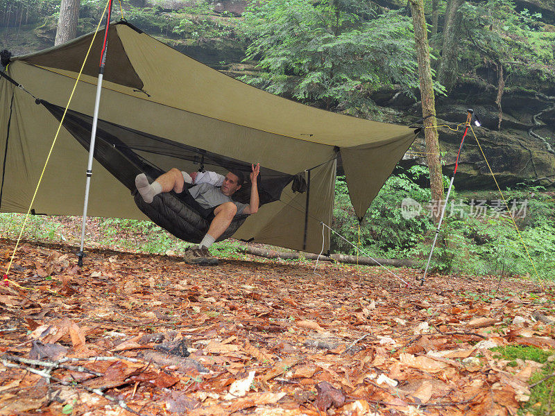 男子在风景优美的露营地的现代露营吊床上