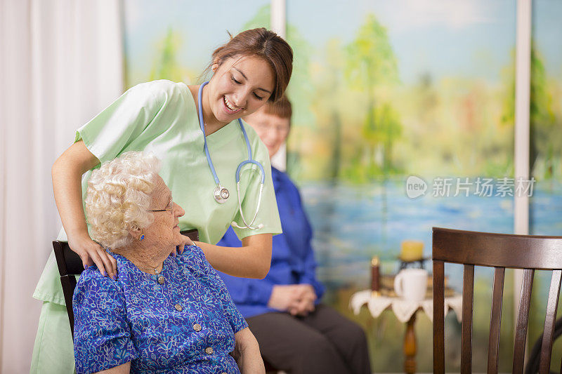 关怀的拉丁后裔护士与她的老年病人谈话。