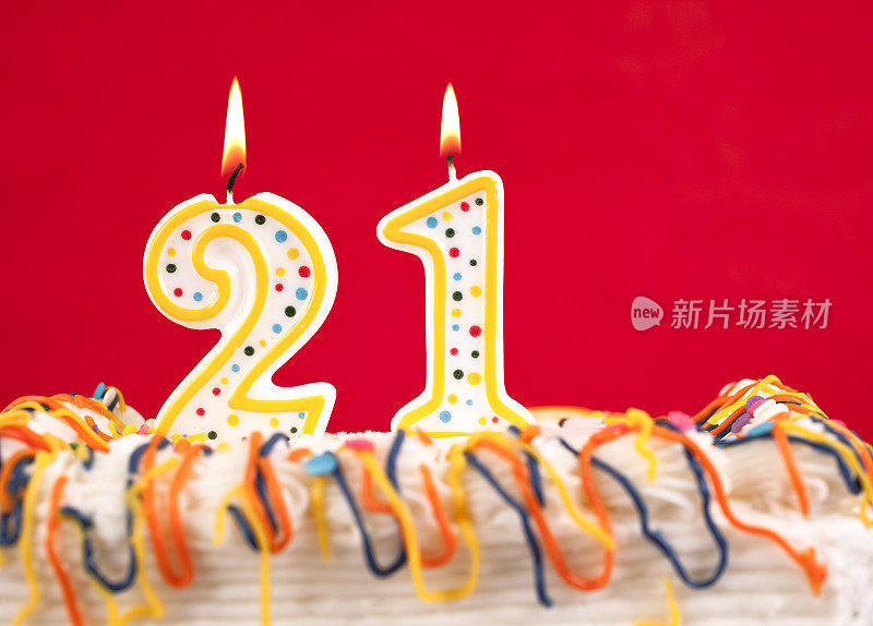 用21号燃烧的蜡烛装饰生日蛋糕。红色的背景。