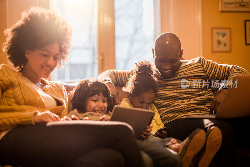 快乐的非裔美国人家庭一起使用无线技术。