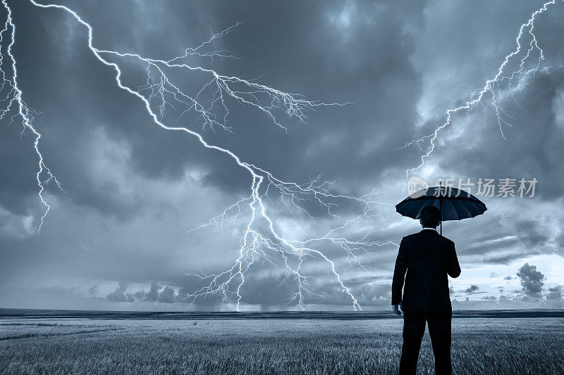 在暴风雨中穿着黑色西装带着黑色雨伞的男人