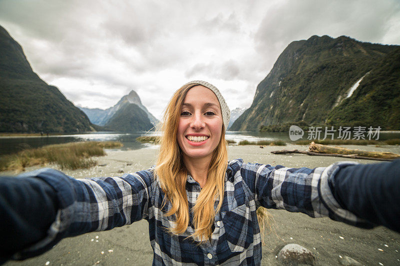 一名年轻女子在旅行中与山景自拍