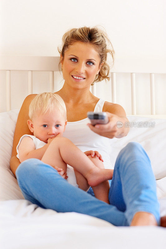 放松的母亲和孩子在卧室看电视