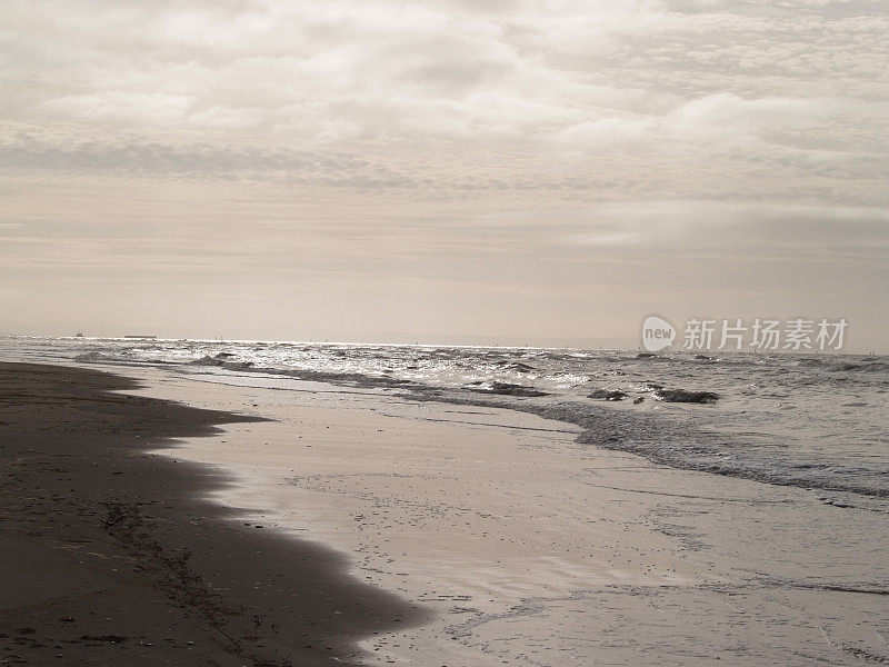 黄昏的海滩上，银色的大海和天空