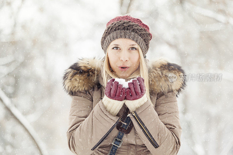 下雪的时候，漂亮女孩手捧雪在户外