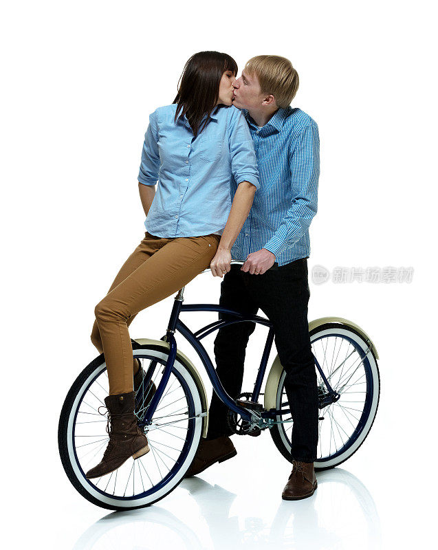 一对情侣坐在自行车上亲吻对方