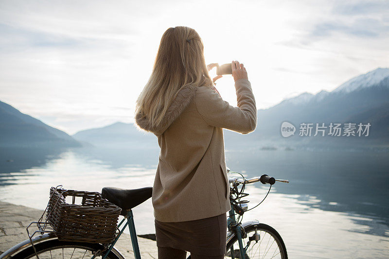 女人骑着自行车在湖边用手机拍照秋天