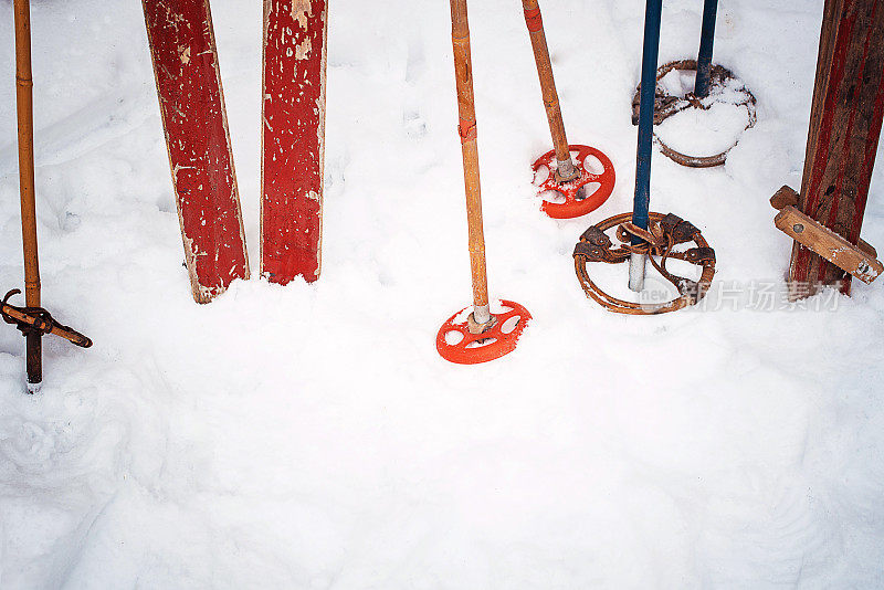 老式复古风格的滑雪板和木棍粘在白色的雪地上