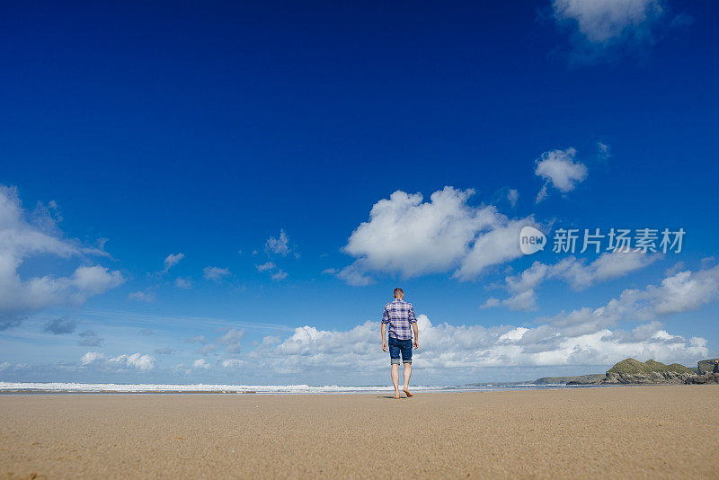 一个人走在水门湾海滩在一个美好的日子。