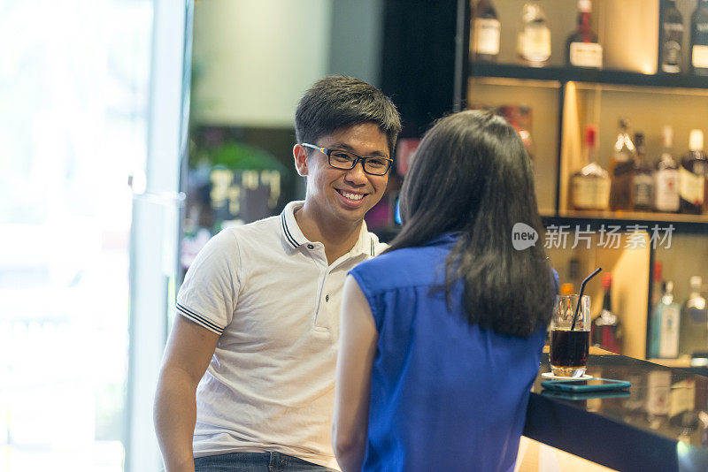 快乐的年轻亚洲夫妇在酒吧聊天