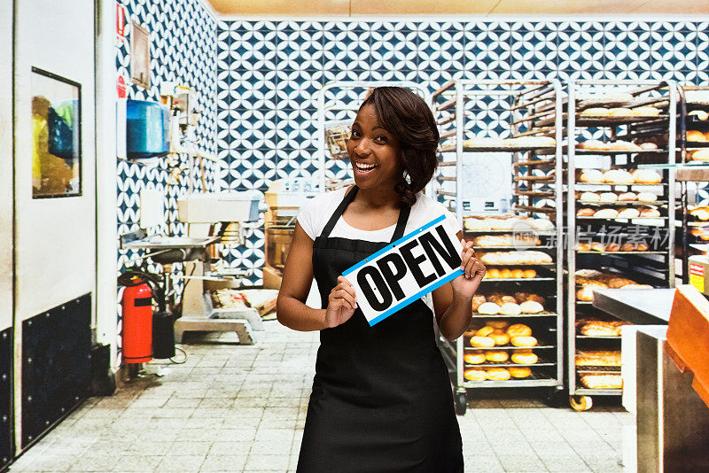 女性面包师举着开放的牌子在面包店
