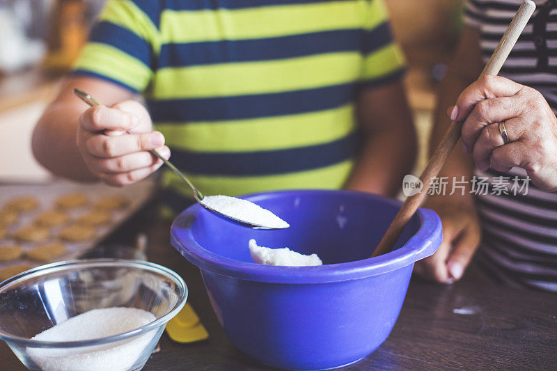 孙子在厨房里帮奶奶烤饼干