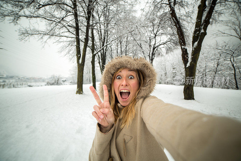 好玩的女人在公园里与雪自拍