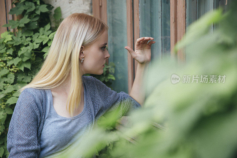 好奇的金发女郎试图透过窗户看一间旧房子