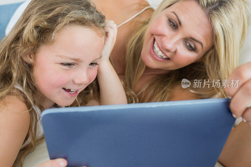 微笑的女儿和母亲使用平板电脑