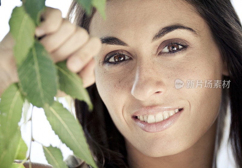 微笑的美人透过树叶