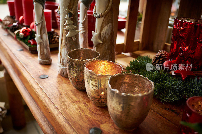 圣诞装饰，复古的样子:桌子上有三个金色的烛台，周围是烛台和木制的人物