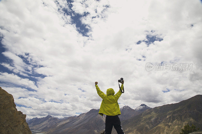 成功的摄影师手持单反相机在山上