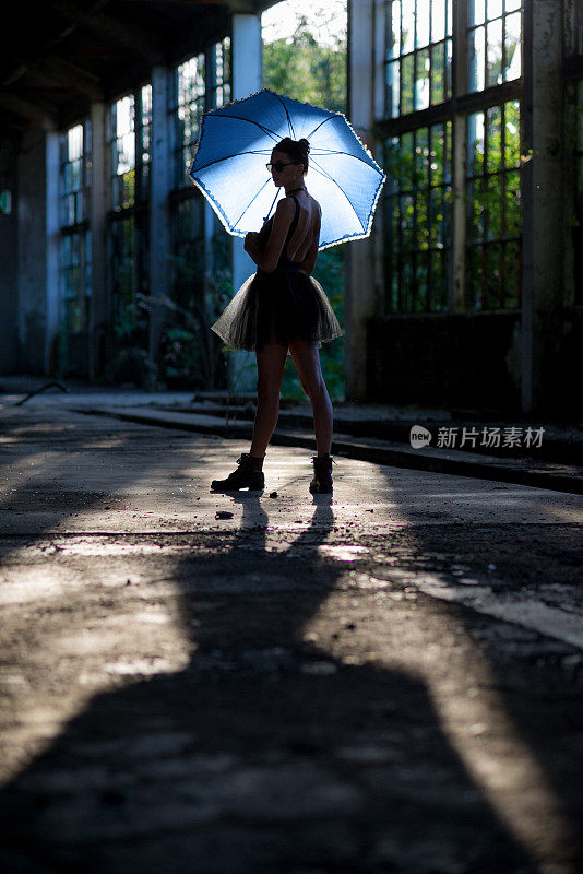 一个穿靴子撑伞的哥特芭蕾舞女演员在一个废弃的建筑里摆姿势