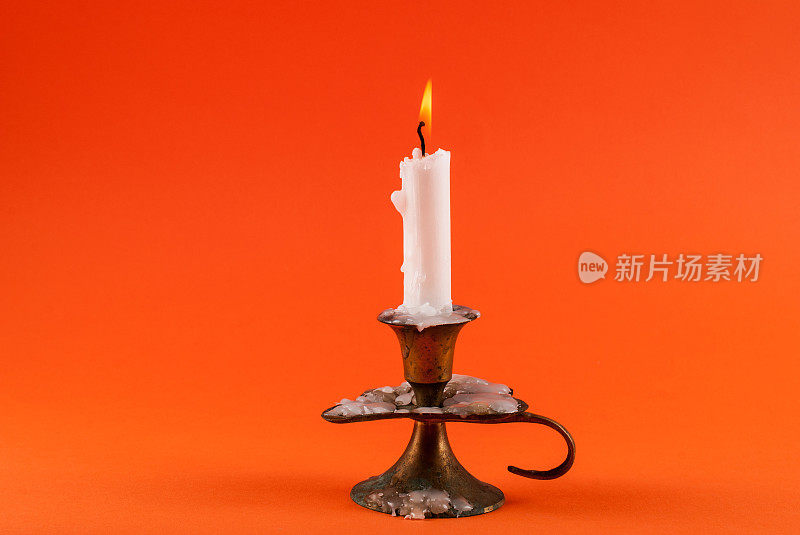 蜡烛在旧烛台上燃烧在橙色的背景和空间设计