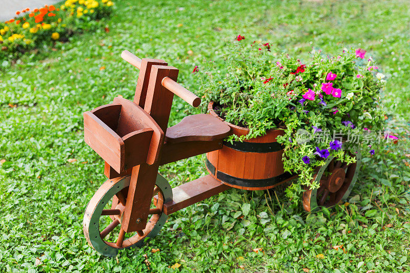 木制自行车形状的花坛。用矮牵牛花装饰花园。