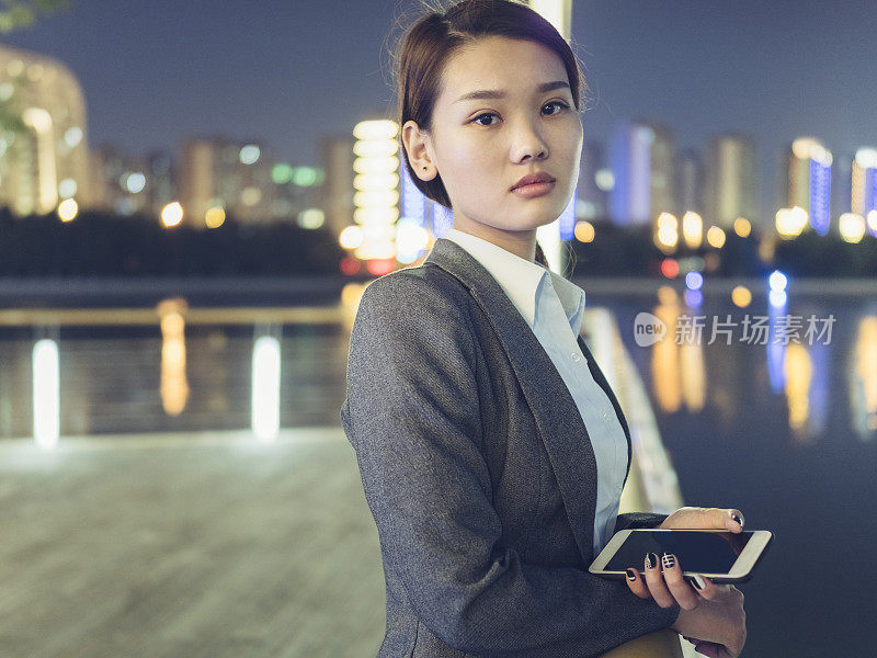 商业女性拿着智能手机站在城市里的肖像