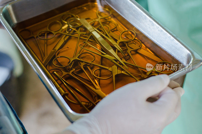 手术理念，手持手术器械在不锈钢托盘中放入洗必泰溶液，在手术室准备手术