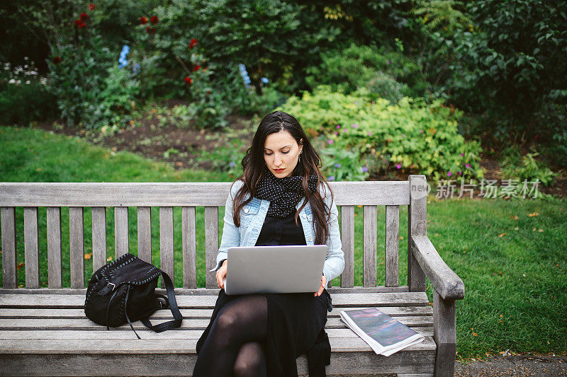 在伦敦公共公园用笔记本电脑工作的黑发女人