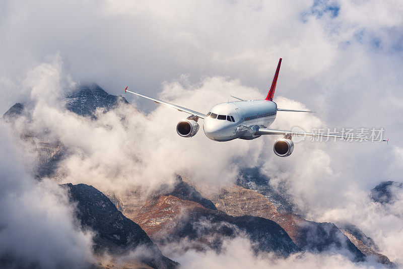 飞机，山在阴天。飞机在高山上的云层中飞行。景观与飞机，多云戏剧性的天空。客机。商务旅行。商用飞机。空中