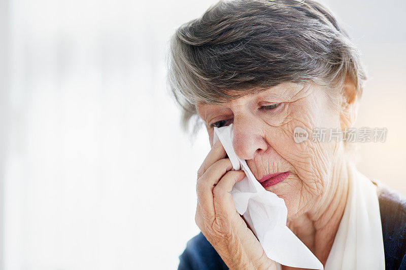 满脸皱纹的老妇人用面巾纸擦眼睛