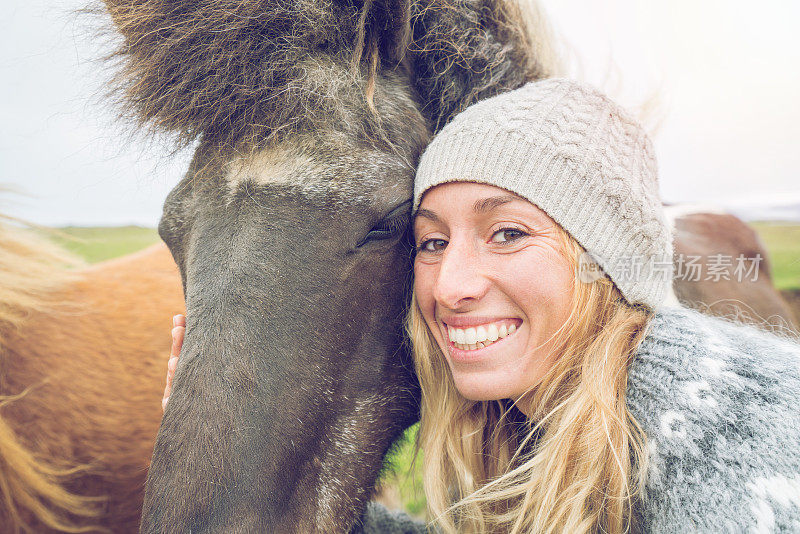 年轻女子拥抱冰岛马在草地，爱动物分享的概念