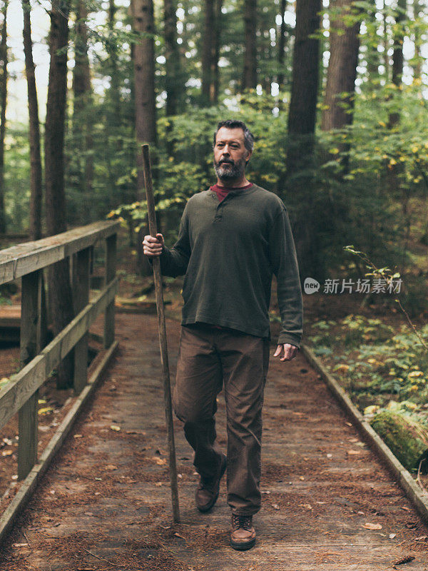 中年男子拄着拐杖在树林里徒步旅行