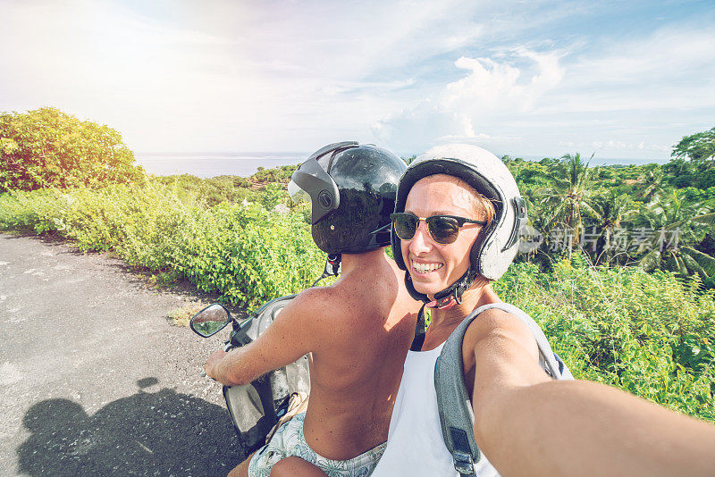 一对年轻夫妇在热带岛屿上骑摩托车自拍