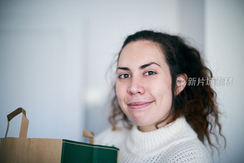 微笑的年轻女子背着购物袋