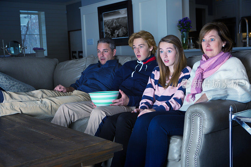 四口之家坐在一起看恐怖紧张的电视