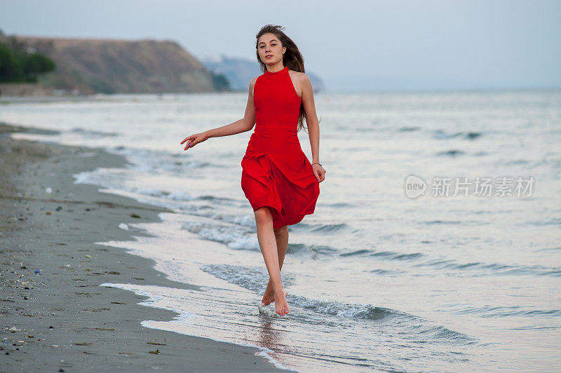 穿红衣服的年轻女子在海滩上跑步