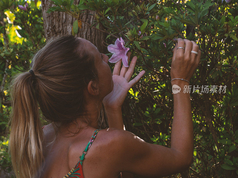 年轻女子照顾植物在异国情调的花园