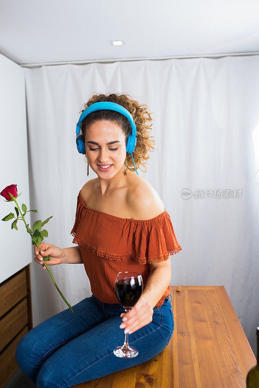 一个漂亮女人的肖像戴着耳机享受最喜欢的歌曲，而坐着喝红酒