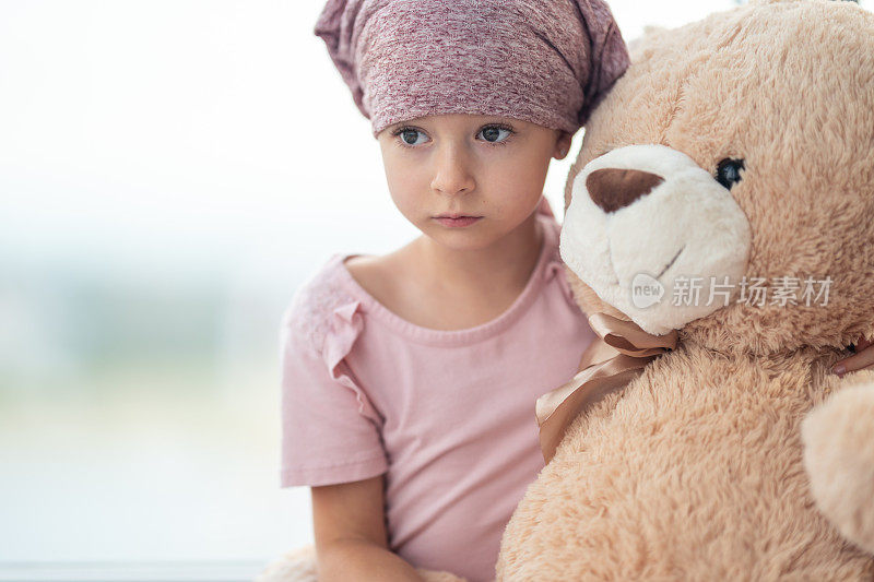 一个身患癌症的女孩拿着毛绒玩具的肖像