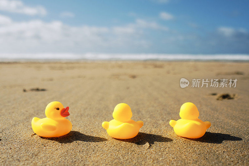 概念上，三个人群，三个橡皮鸭在海滩上，两个面对着海岸。