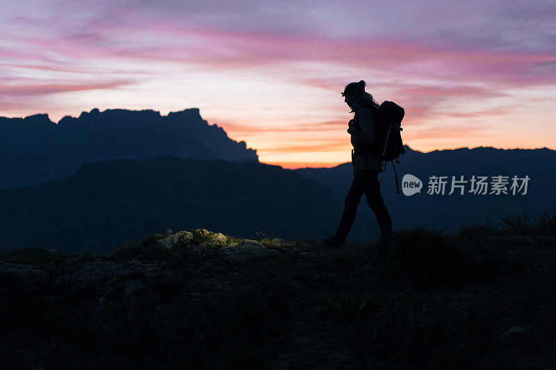 日出时，女徒步旅行者穿过山脊