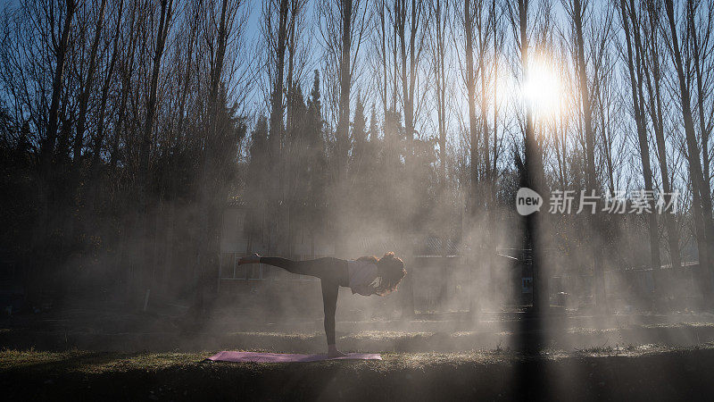 成年妇女在雾蒙蒙的户外做瑜伽练习