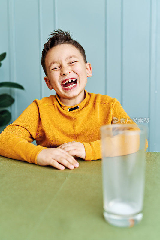 6-7岁可爱的孩子在桌上喝牛奶。他知道他需要喝牛奶来保持骨骼健康。他喜欢牛奶。